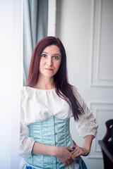 young caucasian funny woman in a sky blue corset and vintage white shirt ready for historical ball dance