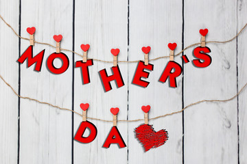 Mother’s day concept. Heart shaped clamps hanging with letters, forming Mother’s day words
