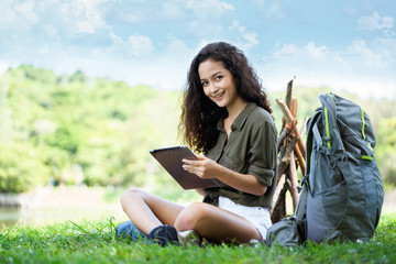 Naklejka na ściany i meble Teenage Woman travelers are sitting on tablet to shop online that involves hiking equipment. And order other items such as food, water, medicine. Summer vacations making you feel relaxed, happy
