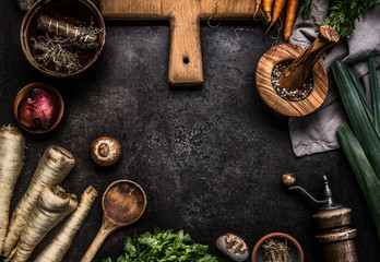 Rustic food background with root vegetables, herbs,spices ,leek and champignon mushrooms on dark rustic table with kitchen utensils, top view. Copy space. Vegetarian food. Healthy cooking and eating