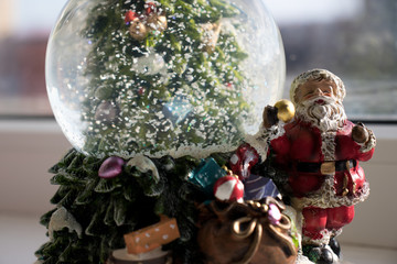 Glass ball with snow along with Santa Claus and gifts