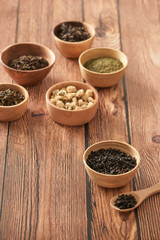 assortment of dry tea in white bowls on wooden surface