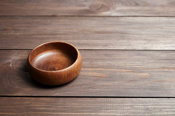 Empty wooden bowl on brown table. Round salad-bowl