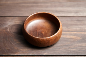 Empty wooden bowl on brown table. Round salad-bowl. Tableware from natural material