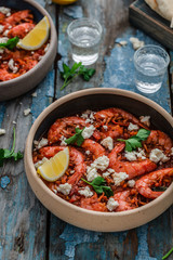 Shrimps saganaki with feta cheese on a plate on a table