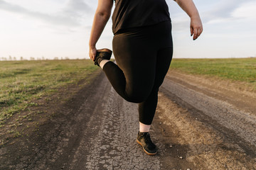 Woman warming up legs before outdoor running. Getting ready for jogging. Sport, activity, healthy lifestyle and weight losing