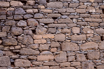 Background texture of a wall of stone of different size brown color folded in rows. The concept of nature and construction. Cropped shot, close-up, horizontal.