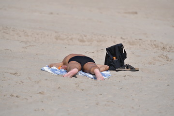An elder man taking a sunbath at a beach in Spain.