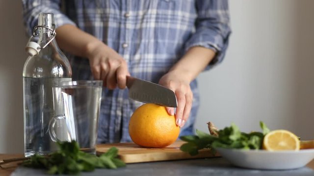 Closeup of a woman cutting a knife ripe red delicious grapefruit on a wooden Board in the kitchen