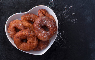 Sweet fried donuts on a heart-shaped plate. The view from the top. Copy space.