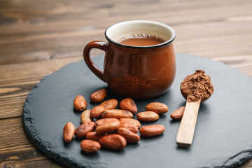 Brown cup of fresh cocoa drink with cocoa beans and powder