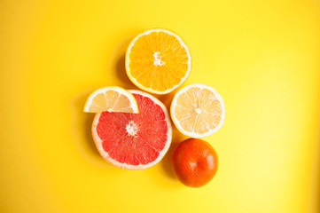 Flat lay of cut ripe juicy grapefruit, lemon and orange on yellow background. Citrus pattern.