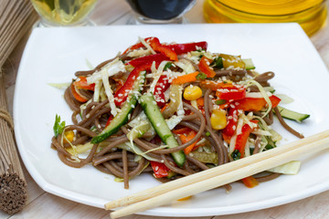 Japanese soba salad with vegetables and sesame close-up on a plate on the table. vegetarian Asian food. noodles salad. buckwheat noodle with vegetables.