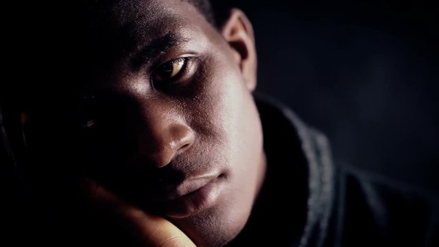 Pensive depressed black african man in the dark.Worries,thoughts