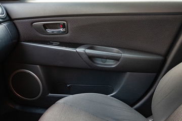 The interior of the car with a view of the dashboard, seats, speaker and door with light gray trim