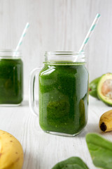 Green smoothie with spinach, avocado and banana in glass jars, side view. Close-up.