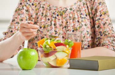 Unrecognizable young woman having fruit salad for breakfast