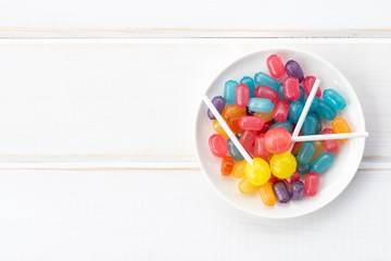 Junk food. Multicolored candies on a plate. Top view, light background.