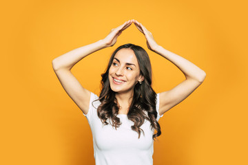 An aura of friendship. Sweet girl in a happy mood is holding her hands above her head to show a sing of true love to her friends.