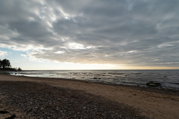 Limestone beach at the Baltic Sea with beautiful sand pattern and vivid red and orange color - Tourist writings on the walls and rocks and sand - Veczemju Klintis, Latvia - April 13, 2019