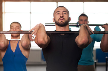 Naklejka premium Young People in Gym Training With Barbells