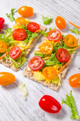 Healthy snack from wholegrain rye crispbread cracker with cherry tomatoes, avocado and salad. Proper nutrition.