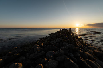 Boulder beach pier sunset with vivid red and orange colors on the Baltic Sea - Tuja, Latvia - April 13, 2019