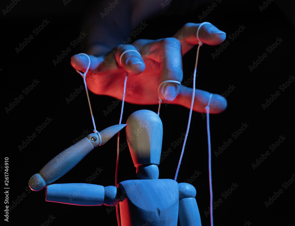 Wall mural Concept of control. Marionette in human hand. Objects are colored on red and blue light.