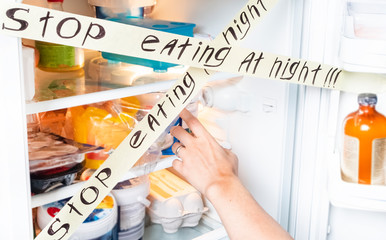 Healthy lifestyle. The girl looks at food at night, wants to eat and pulls a hand to the products