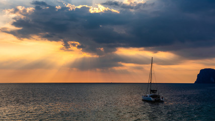 Naklejka na ściany i meble Light of sun pass through clouds with yacht in sea