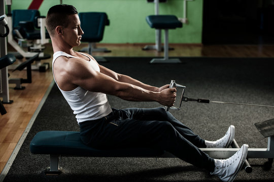 phisique fitness competitor works out in gym lifting dumbbells