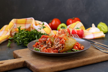 Stuffed peppers with meat, rice and tomato sauce located on a dark background