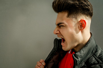 young brunette guy and model with a fashionable haircut and styling in a black jacket on a wooden background with a place for the inscription