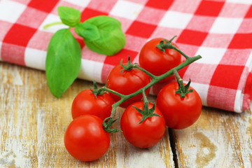 Fresh cherry tomatoes and fresh basil leaves on red and white checkered cloth