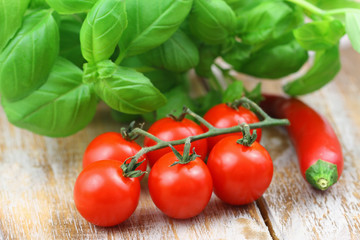 Ingredients for perfect pasta: ripe cherry tomatoes, fresh basil leaves and chilli on rustic wooden surface