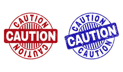 Grunge CAUTION round stamp seals isolated on a white background. Round seals with grunge texture in red and blue colors. Vector rubber watermark of CAUTION title inside circle form with stripes.