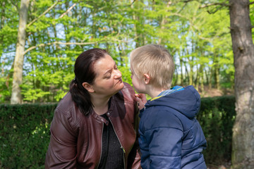 Defect,childcare,medicine and people concept: Happy mother and son with down syndrome playing together in a park at spring time.