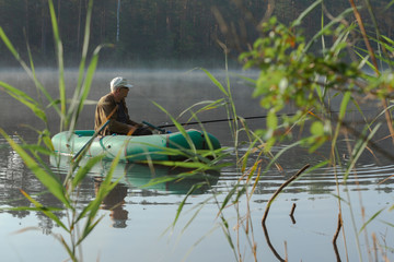 Fisherman in the boat at the forest lake