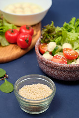 fresh vegetables and a bowl of salad with mozzarella on a blue background.  Caprese salad . Lettuce, cherry tomatoes, mozzarella, 