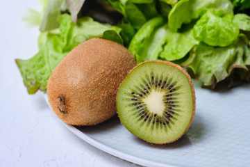 kiwis, lettuce and cherry tomatoes on a white plate on a white background