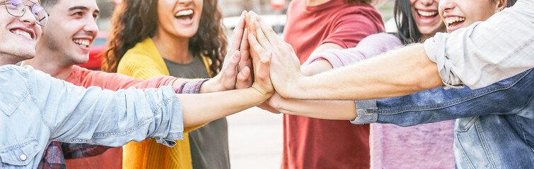 Group of diverse friends stacking hands outdoor - Happy young people having fun joining and...
