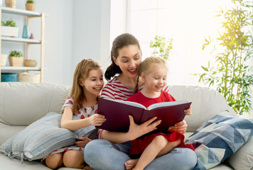 mother reading a book to daughters
