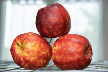 Ripe, colorful mottled apples on a grate and background of a bright window.