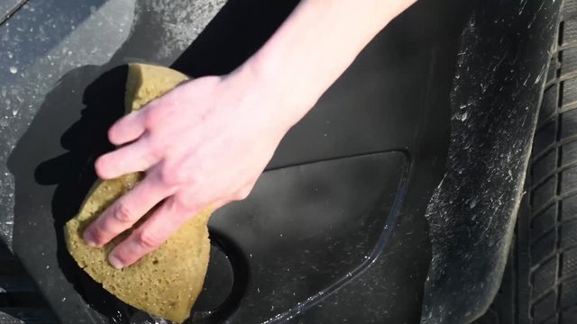  close up male hand with foam sponge washing car plastic bumper. bottom view. Concept: Auto Car Service, Car Wash