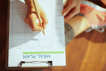 Closeup on healthy woman with clipboard filling meal plan