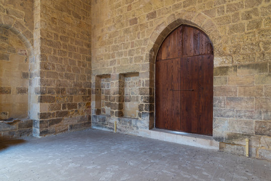 Arched wooden door and two embedded niches in stone bricks wall, at the public Mosque attached to Al-Muayyedi Bimaristan historic building, Old Cairo, Egypt