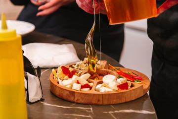 Cheese plate: the cook pours honey into the cheese