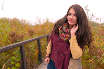 A gorgeous romantic young woman with beautiful long brown hair enjoying the autumn weather in the local park, filled with the joy of fall. It's her favorite season