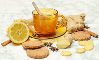 Obraz na płótnie Canvas A yellow cup of tea, with ginger roots, lemon and spices. A healthy lifestyle, anti-flu and anti-inflammatory concept.