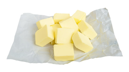 Fresh butter cut into pieces for making sauce or shortbread dough. Pieces of butter on white paper packaging. Natural fat nutrient. Isolated.